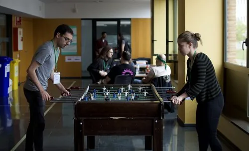 Des joueurs penchés sur un baby-foot, vus de côté, avec l'espace libre autour de la table.